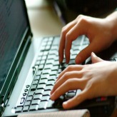 Hands typing on laptop keyboard.